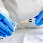 Doctor fills injection syringe with vaccine