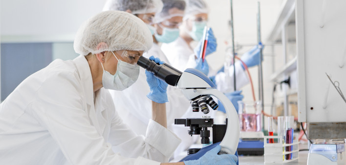 Scientists in protective suits in a science laboratory study a virus