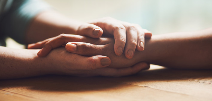 Shot of two people holding hands in comfort