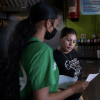 Melissa Lopez explains the COVID testing process to a taco shop employee in Fresno, California, as part of her training as a health educator.