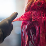 Young woman getting her hair dyed a vivid red in salon
