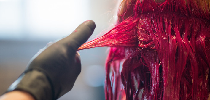 Young woman getting her hair dyed a vivid red in salon
