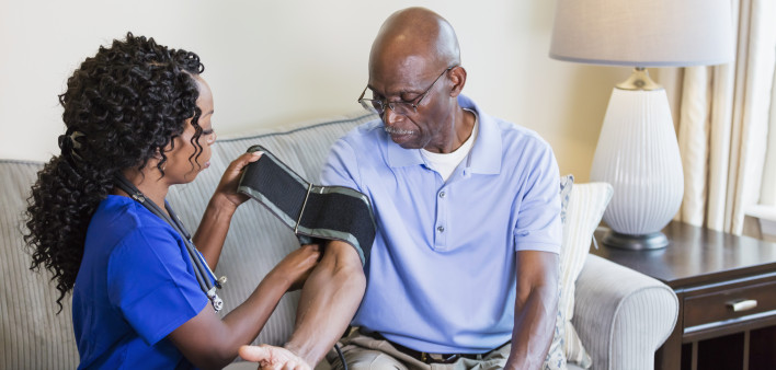 Home nurse checking senior man's blood pressure