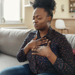 Pressure in the Chest. Close-up Photo of a Stressed Obese African American Woman Who Is Suffering From a Chest Pain and Touching Her Heart Area.