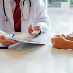 Doctor and female patient discussing while using digital tablet at hospital.