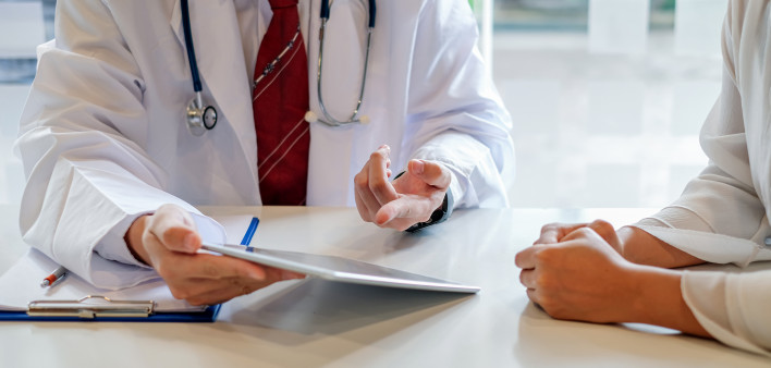 Doctor and female patient discussing while using digital tablet at hospital.