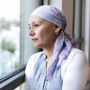 woman with cancer in head scarf looking out window