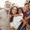 Three generation Hispanic family standing in the park, smiling