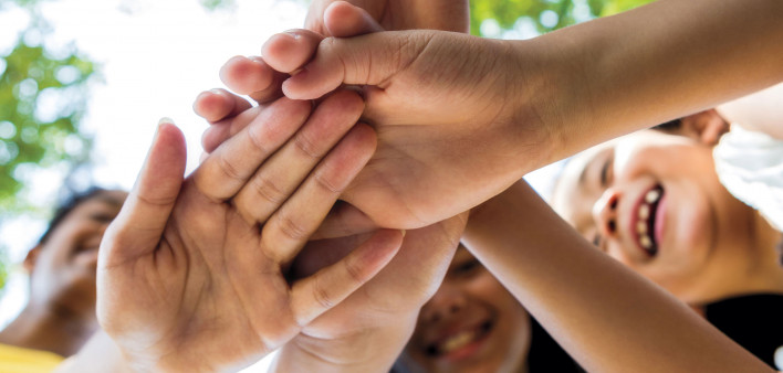 happy young people with hands joined in center