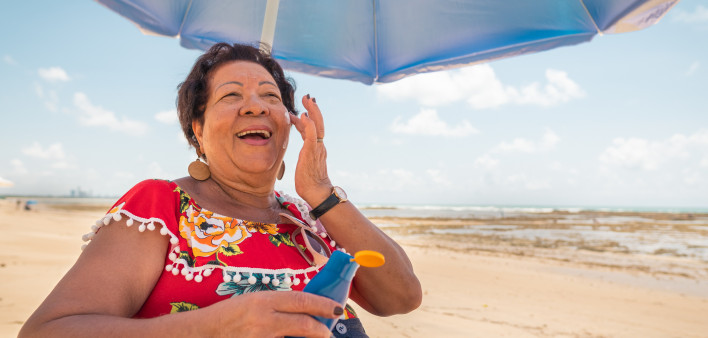 Senior woman using a suntan lotion on the beach