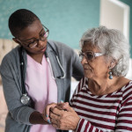 Black nurse comforts older woman