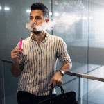 oung hispanic businessman smoking an electronic cigarette