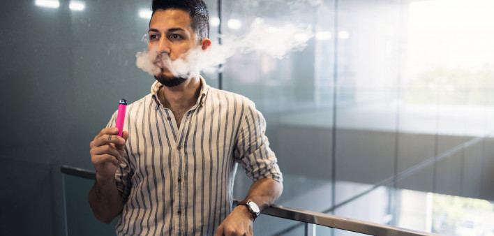 oung hispanic businessman smoking an electronic cigarette