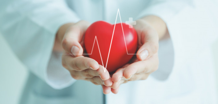 Female medical doctor holding red heart shape in hand with graphic of heart beat, cardiology and insurance concept