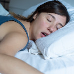 Face close up portrait of woman sleeping in bed and snoring