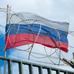 Russian flag behind barbed wire against cloudy sky stock photo Russia, Authority, Prison,