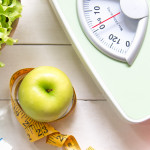 Green apple and Weight scale,measure tape with fresh vegetable, clean water and sport equipment for women diet slimming