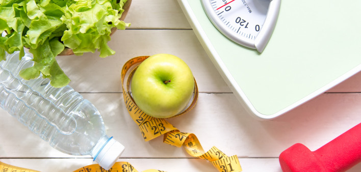 Green apple and Weight scale,measure tape with fresh vegetable, clean water and sport equipment for women diet slimming