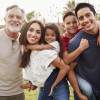 Three generation Hispanic family standing in the park, smiling