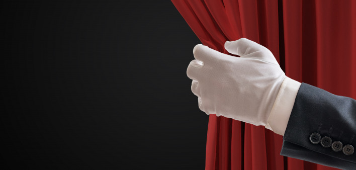 Actor is pulling red curtains in theatre with hand. white glove