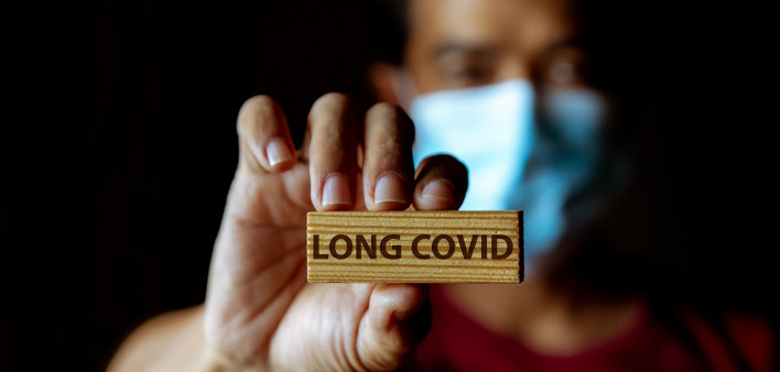 Masked Asian man show wooden sign with wording "Long Covid"
