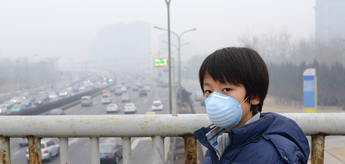 Asian child protects himself against air pollution by wearing mouth mask