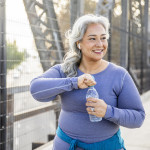 A senior Mexican woman drinking water after a workout
