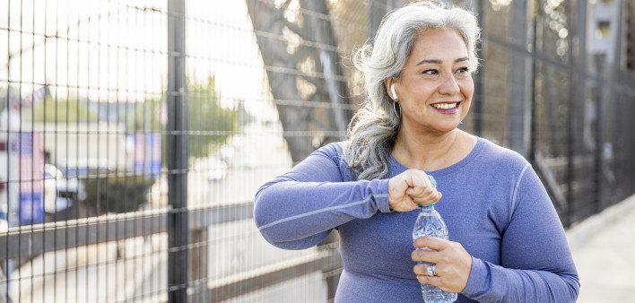 A senior Mexican woman drinking water after a workout