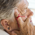 old woman with red string tied around index finger