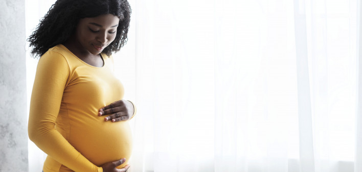 Beautiful pregnant african woman hugging her tummy