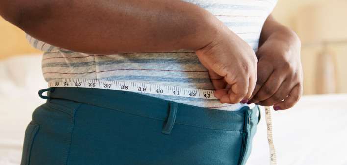 Close Up Of Overweight Woman Measuring Waist At Home Standing Still