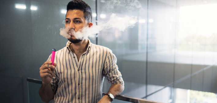 oung hispanic businessman smoking an electronic cigarette
