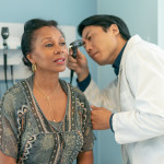 Mature adult woman has ears checked by doctor at routine medical appointment