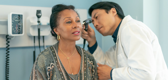 Mature adult woman has ears checked by doctor at routine medical appointment