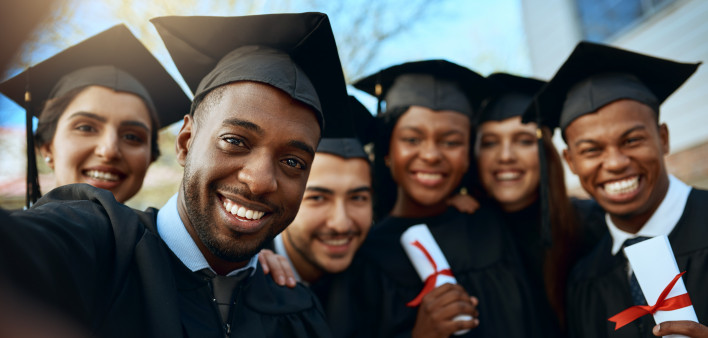 Portrait of a group of students taking selfies on graduation day