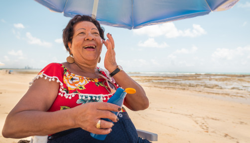 Senior woman using a suntan lotion on the beach