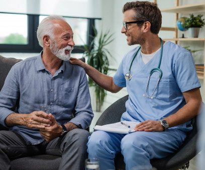 Happy doctor talking to senior male patient while being in a home visit.