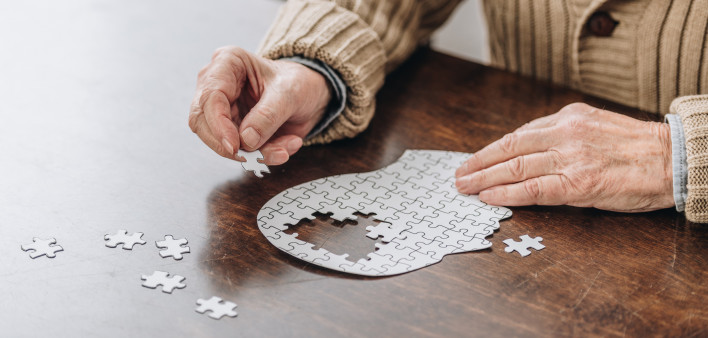 mans hands putting together puzzle pieces to make a head