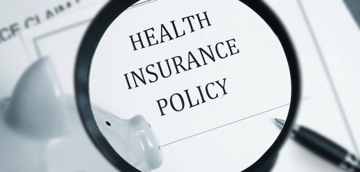 A maginfying glass looking at the words "Health Insurance Policy"