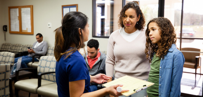 Young Latina girl and mother listen to nurse