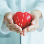 Female medical doctor holding red heart shape in hand with graphic of heart beat, cardiology and insurance concept