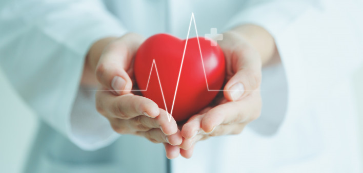 Female medical doctor holding red heart shape in hand with graphic of heart beat, cardiology and insurance concept