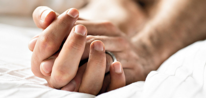 gay male lovers in bed holding hands