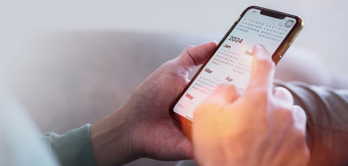 hands holding phone showing calendar