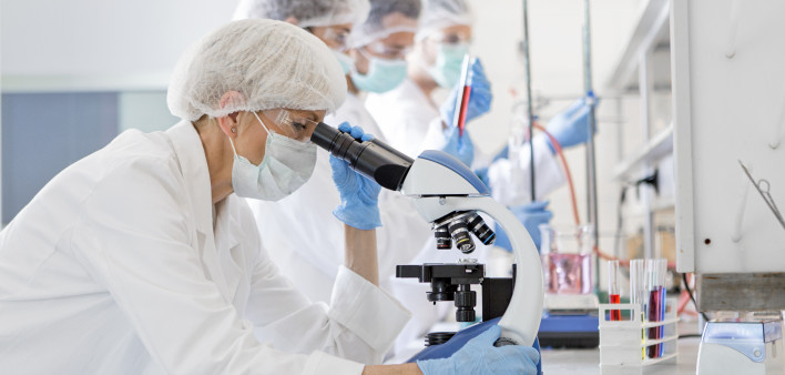 Scientists in protective suits in a science laboratory study a virus