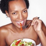 African American woman eating a salad from a bowl