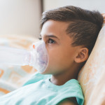 Woman with son doing inhalation with nebulizer at home