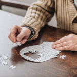 mans hands putting together puzzle pieces to make a head