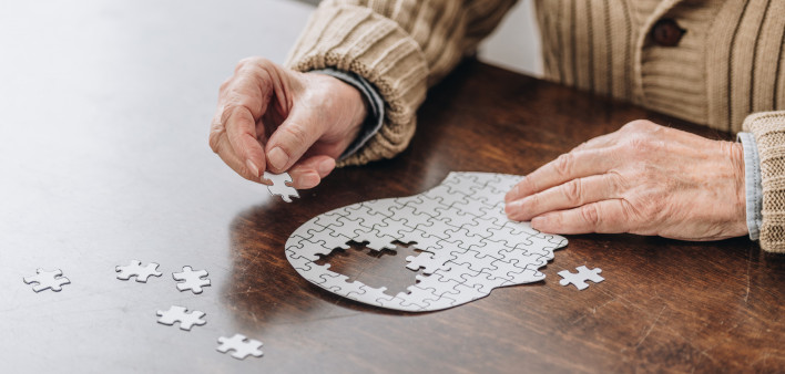 mans hands putting together puzzle pieces to make a head