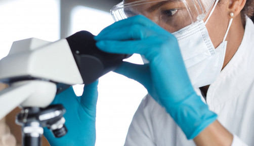 scientist looks through microscope